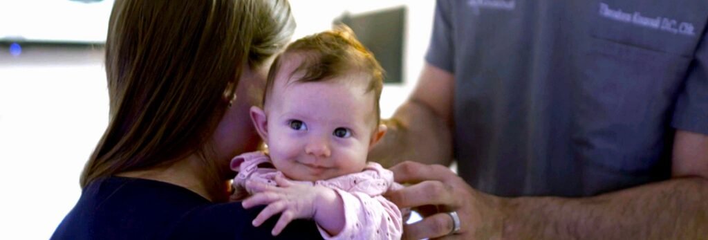 Dr. Theo Kousouli providing gentle chiropractic care for a mother and newborn baby